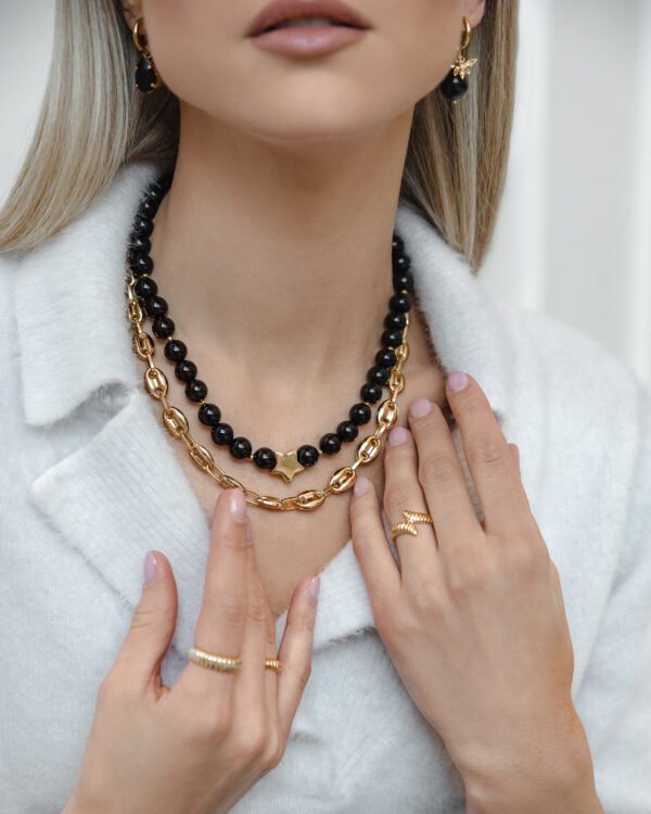 Juodo onikso vėrinys su aukso spalvos grandinėle.